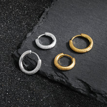 Simple frosted round circle 925 sterling silver and 18K yellow gold hoop earrings on dark stone background.